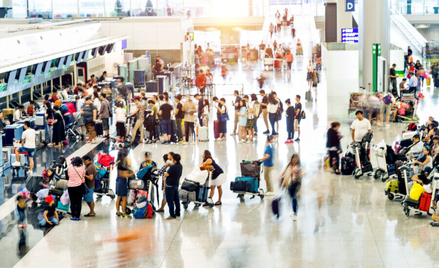 To Fly or to Drive? That Is the Question. - 2 Busy airport terminal filled with travelers ready to fly, waiting in lines, moving with luggage, and checking in at counters under bright lighting.