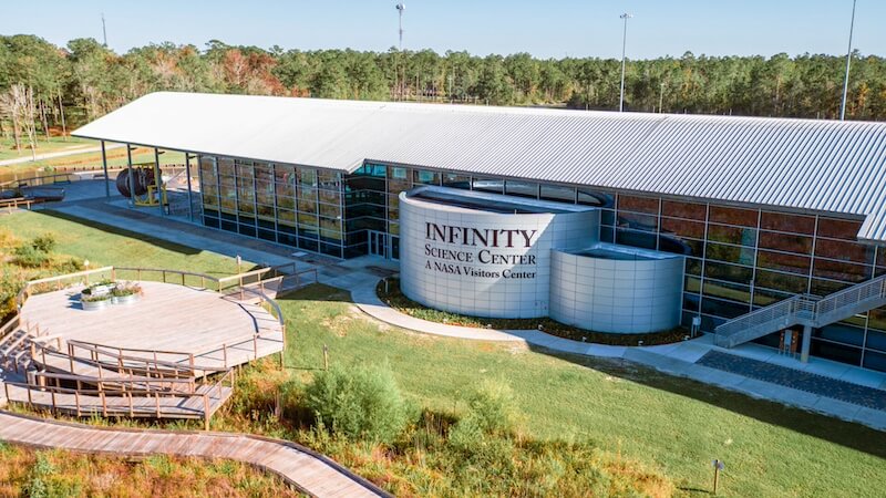 Mississippi, Reimagined: A Different Kind of Spring Break Guide - 6 Exterior view of the Infinity Science Center in Mississippi, a NASA visitor center, featuring large glass windows, a curved entrance, and surrounding greenery—perfect for a Spring Break adventure.