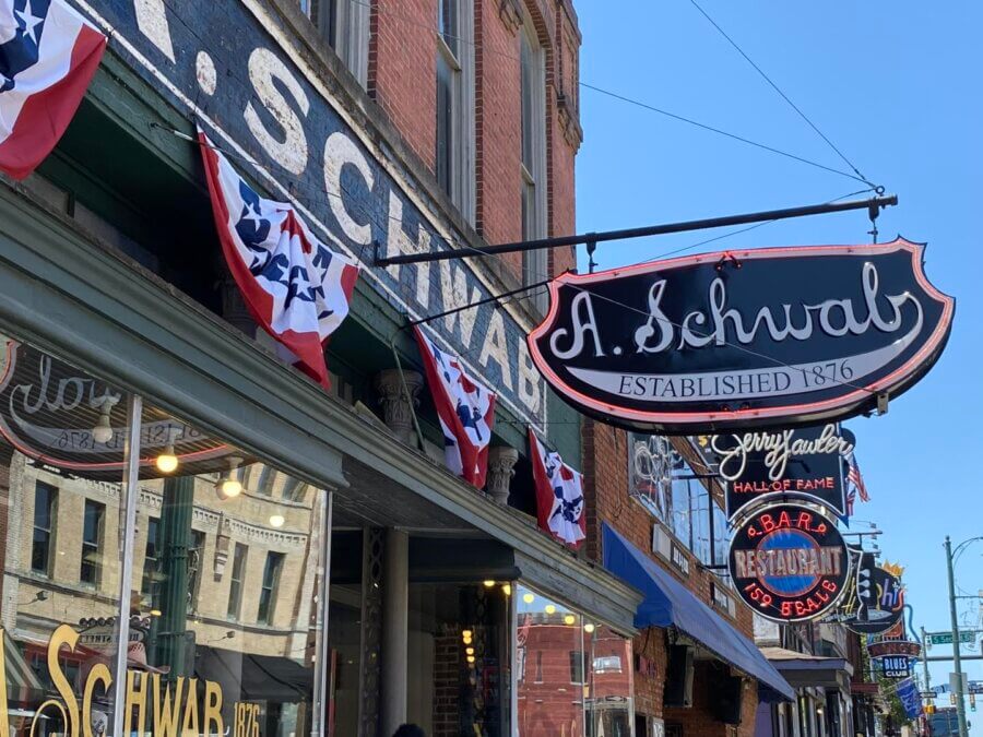7 Best Candy Shops in Memphis (+ One Local Fave You Can Shop Online) - 6 Storefront of A. Schwab, established 1876, with patriotic bunting and signs for a jewelry store and restaurant—one of the best candy shops in Memphis—captured on a sunny day.