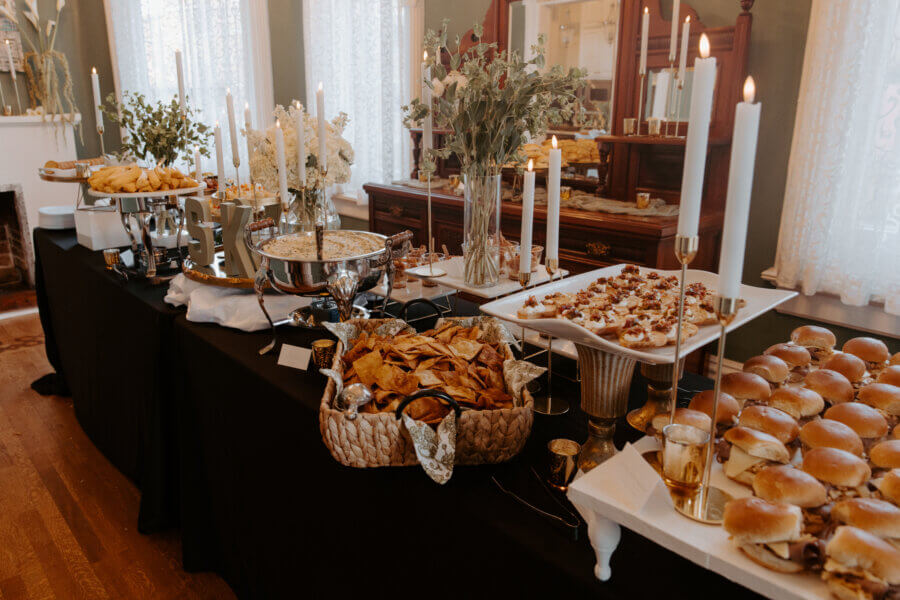 An Elegant Memphis Wedding at The Historic James Lee House - 16 A large catering table filled with heavy hors d’ouvres and beautifully lit with tall, white candle sticks.