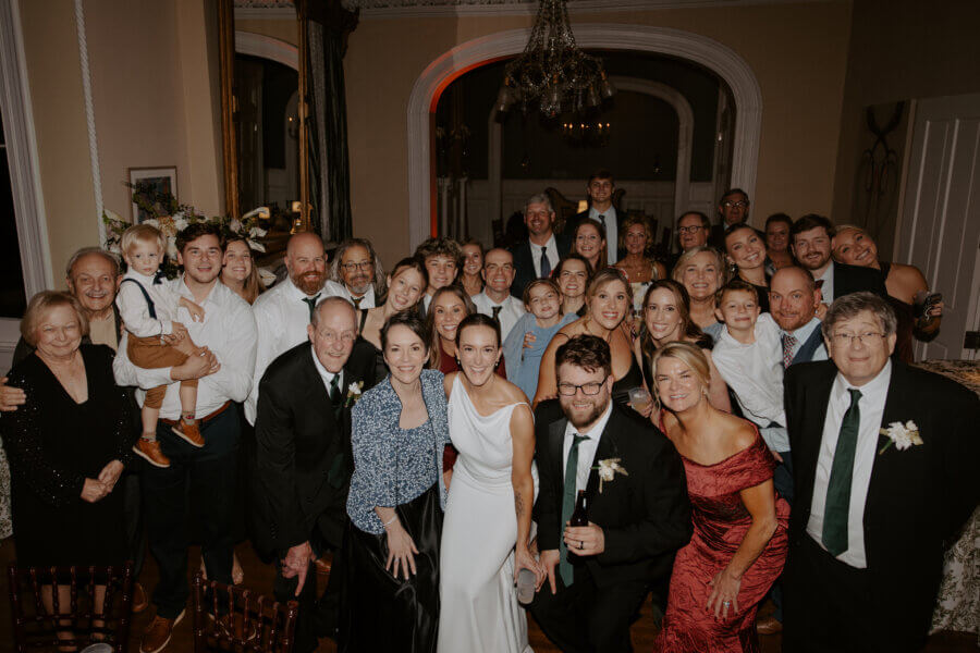 An Elegant Memphis Wedding at The Historic James Lee House - 18 A large group photo taken at a wedding reception, the bride and groom in the middle.