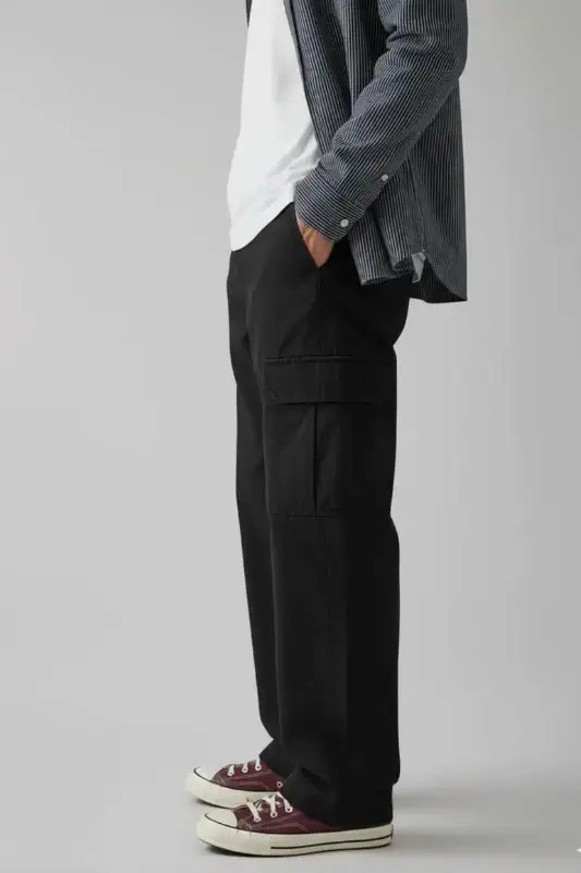 15 Memphis FINDS to See You Through January - 14 A person stands sideways wearing black cargo pants, a white t-shirt, a striped shirt, and maroon sneakersβshowcasing stylish New Year finds against a plain background.
