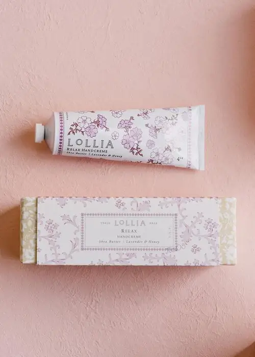 15 Memphis FINDS to See You Through January - 3 A floral Lollia Relax handcreme tube and its matching decorative box are displayed on a pink textured surfaceβan elegant addition to your Memphis Finds for the New Year.