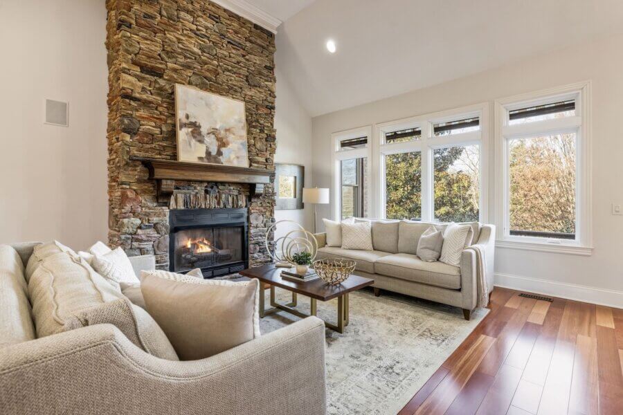 Just Listed! A Franklin Home Designed to Entertain & Unwind - 6 Just listed Franklin home featuring a living room with light sofas, a wooden coffee table, and stone fireplace. Large windows fill the space with natural light, and artwork above the mantel creates an area designed to entertain.