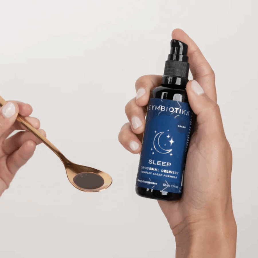 16 Nashville FINDS for a Winter Refresh - 2 A person holds a Cymbiotika Sleep supplement bottle in one hand and a gold spoon filled with the liquid supplement in the other, embracing a Winter Reset inspired by Nashville FINDS.