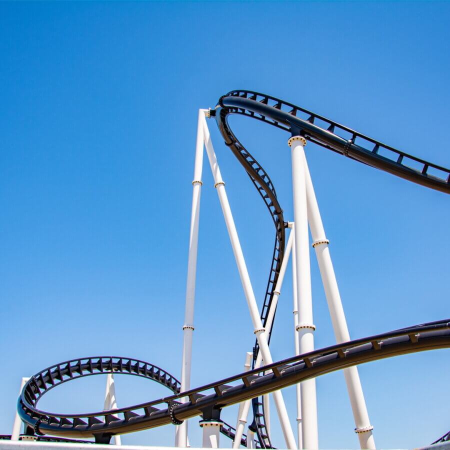 Coming in 2026! Exciting Developments to Watch Around the South - 9 A roller coaster with black tracks and white supports twists against a clear blue sky, hinting at exciting developments in the south set to unfold by 2026.