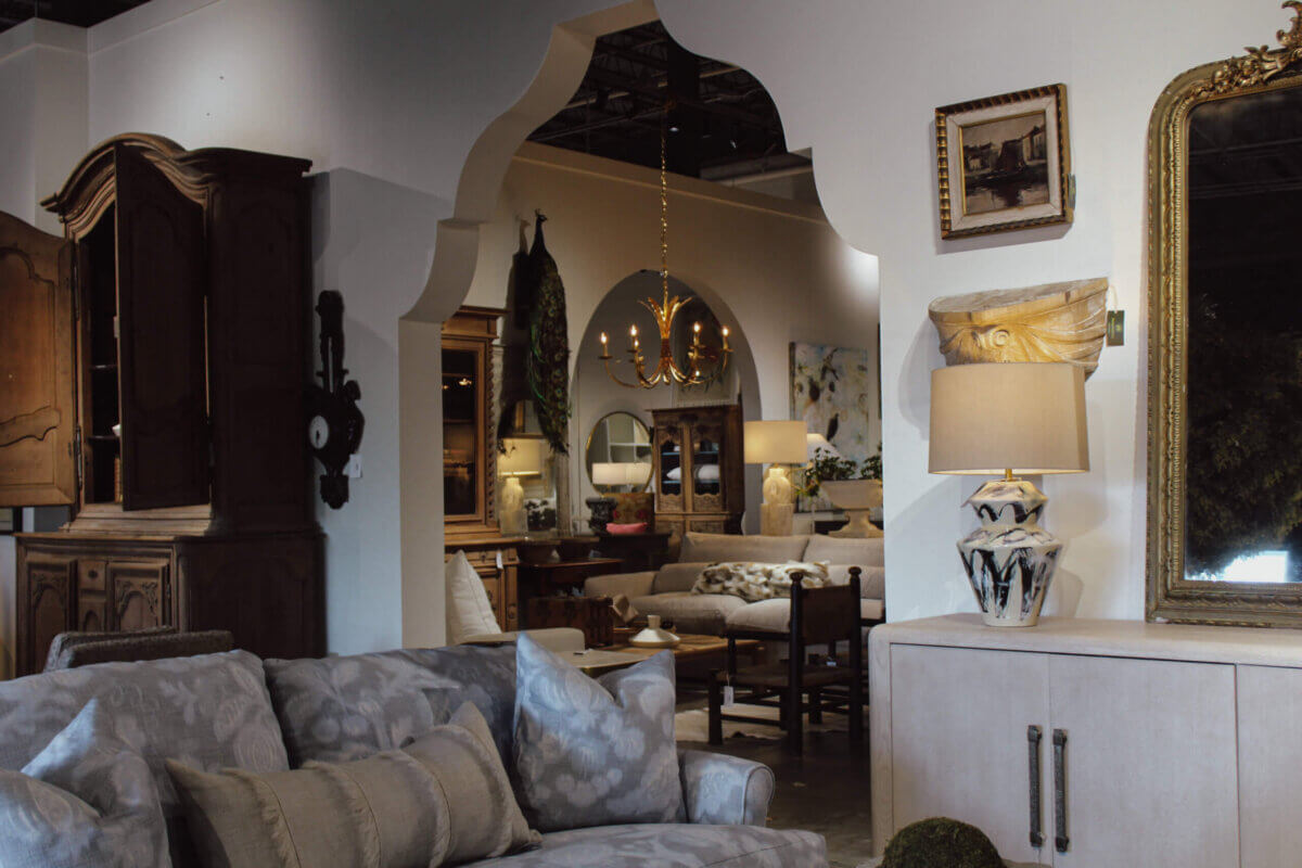 The Top Home Stores in Memphis - 5 A living room with patterned sofas, wooden furniture, a decorative archway, a chandelier, lamps, and mirrors—each piece thoughtfully chosen from home decor stores to create a warmly lit and inviting space.