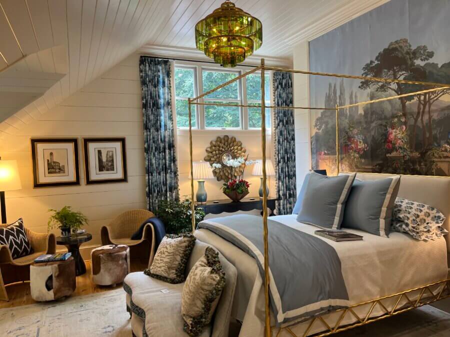 7 Designer Show Houses to Have on Your Radar for 2026 - 5 A spacious, well-lit bedroom inspired by show houses, featuring a gold canopy bed, blue and white bedding, a large wall mural, seating area, plants, framed art, and a striking green chandelier.