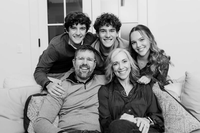 This Nashville Mom Transformed Her Grief Into a Lifeline for Youth - 8 A family of five poses, smiling, on a couch. Two adults sit in front while three teenagers stand close behind them, all looking at the camera—a joyful moment supported by the Goldfinch Foundation.
