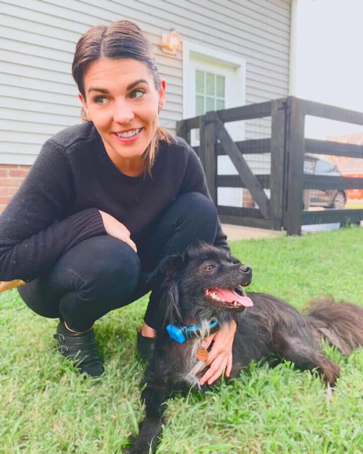 She Connects Pets & People at Nashville Humane Association - 5 Laura Baker sits in the grass, smiling, with her dog.