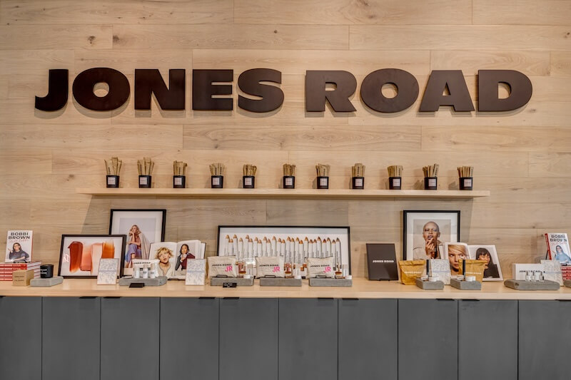 6 New Nashville Services to Elevate Your Everyday - 3 A display of everyday makeup products and framed photos sits beneath large "JONES ROAD" signage on a wooden wall in a cosmetic store, ready to elevate your beauty routine.