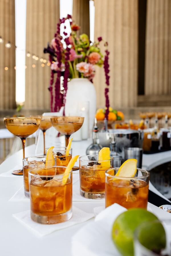 A Gold-Washed Wedding at Nashville's Iconic Parthenon - 10 A table set for a Golden Parthenon wedding, adorned with glasses of alcohol and fresh fruit.