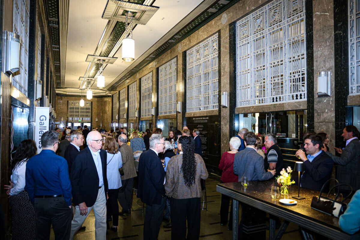 Guests socialize at a crowded reception in an ornate hall, one of many Nashville event spaces featuring high ceilings, marble walls, and large metal window grilles.