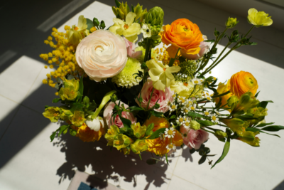 A bouquet of assorted flowers, including yellow, white, and pale pink blooms, sits on a sunlit white surface—an elegant arrangement inspired by the artistry of Birmingham florists.