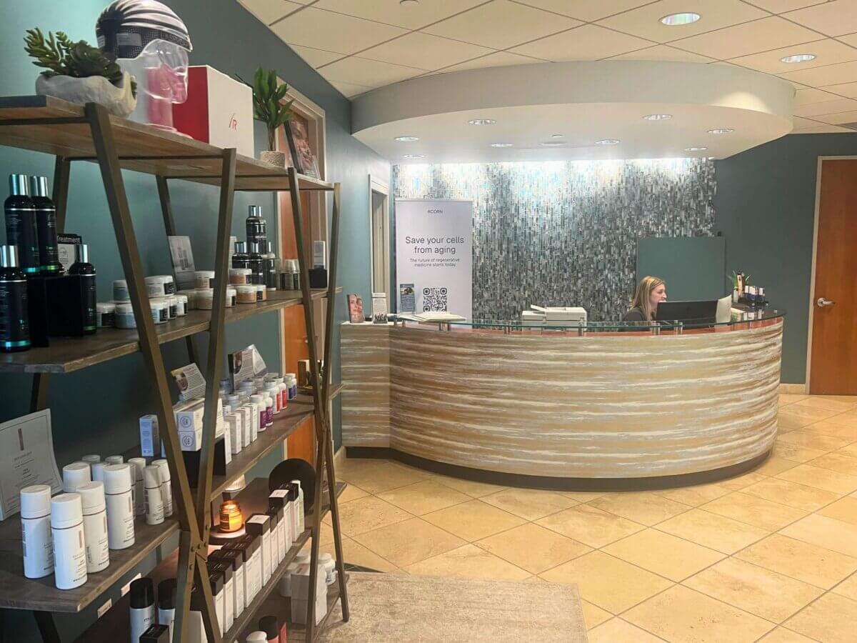 The Top Hair Salons in Nashville - 9 Modern reception area with a curved desk, a receptionist working, and shelves displaying skincare products on the left—capturing the welcoming atmosphere you’d expect from one of the best salons in Nashville.