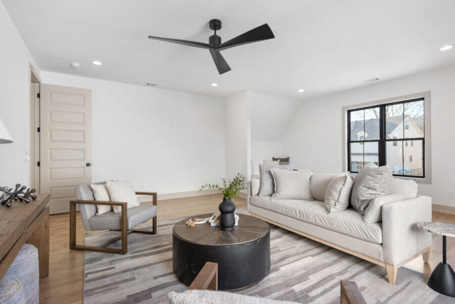 Modern living room at 506 Stonewall Way, Brentwood TN, with neutral decor, a sofa, armchairs, round coffee table, ceiling fan, and a large window letting in natural light.