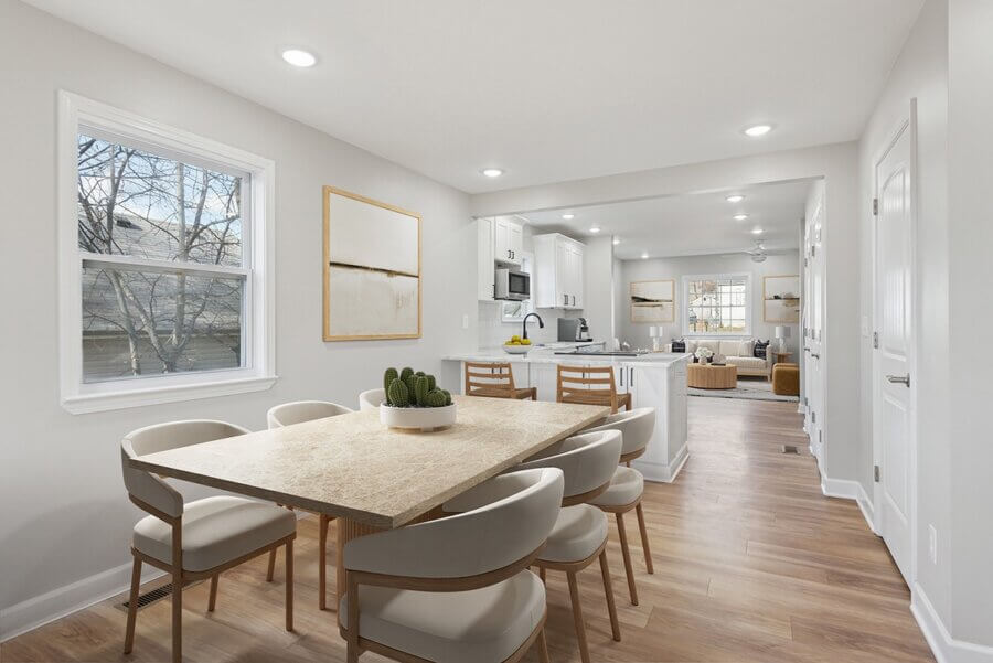 Modern dining area with a light marble table and six chairs at 112 Wiley St, Madison TN, adjacent to a white kitchen and open living room, featuring wood-style flooring and neutral decor.