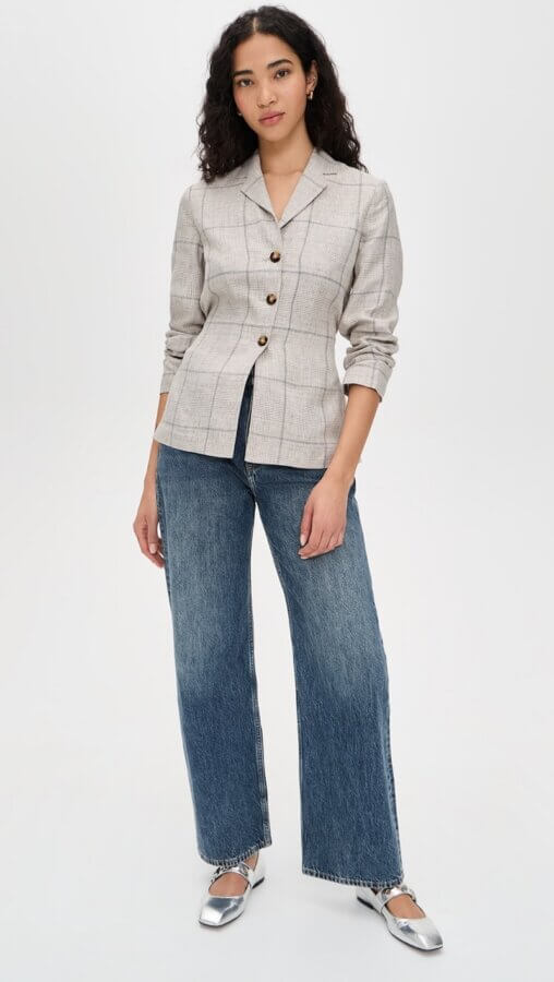 6 Spring 2026 Fashion Trends + How to Wear Them - 3 A person stands wearing a plaid blazer with large buttons, wide-leg blue jeans, and silver ballet flats against a plain white background.
