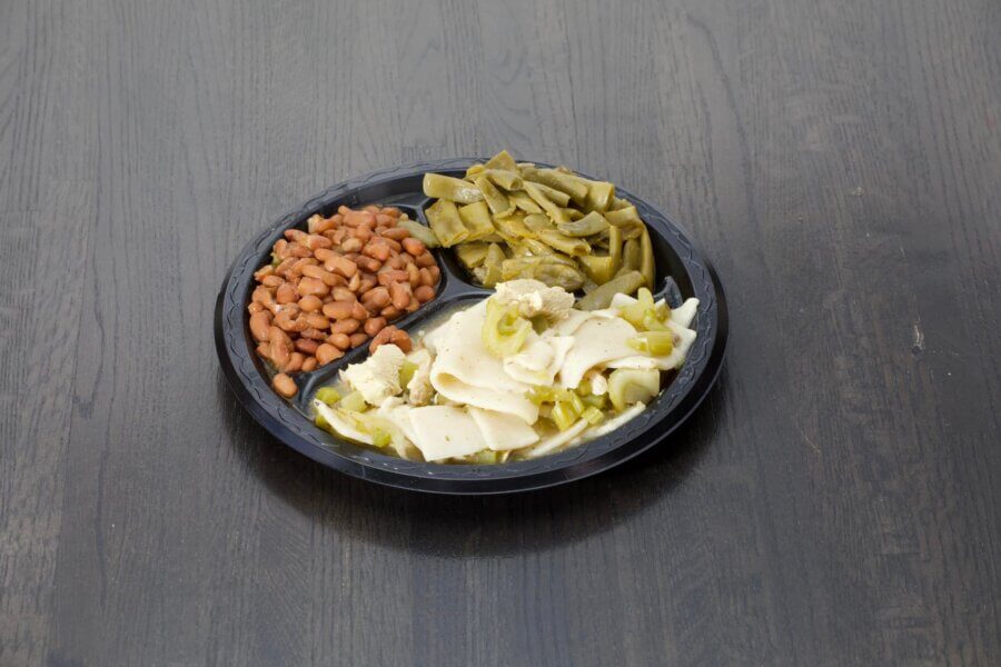 10 New Birmingham Restaurants to Try This Month - 12 A black plastic tray with three sections containing pinto beans, cooked cactus strips (nopales), and a mix of pickled vegetables on a dark wooden surface.