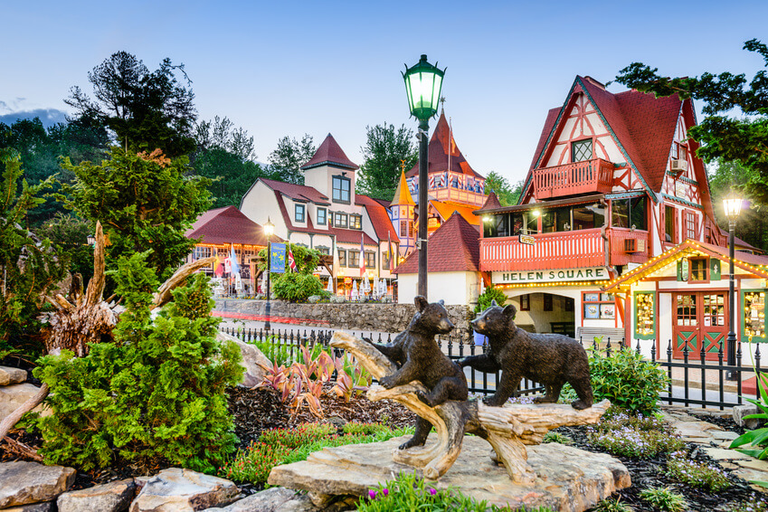 How to Eat, Shop & Explore Your Way Through Georgia - 4 A quaint village scene with Alpine-style buildings, lush landscaping, and a statue of two bear cubs in the foreground, labeled Helen Square—an inviting spot to Eat, Shop, Play Georgia style.