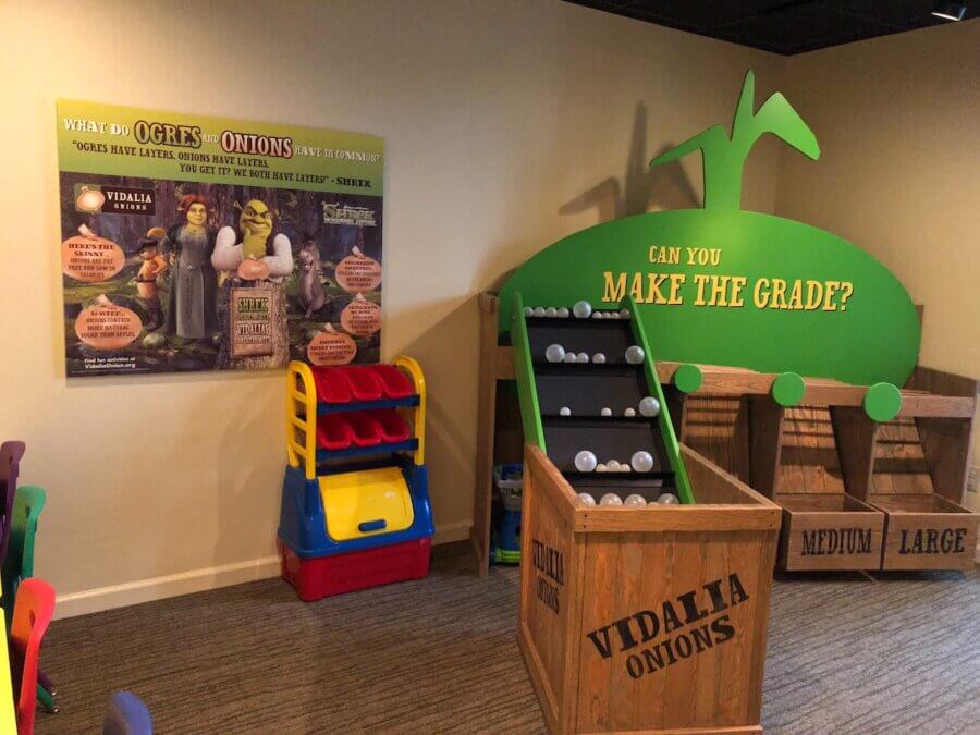 How to Eat, Shop & Explore Your Way Through Georgia - 2 Children’s play area with onion-themed displays, including bins labeled “Medium” and “Large,” a ball toss game, and a poster about ogres and onions—perfect for families looking to play in Georgia.