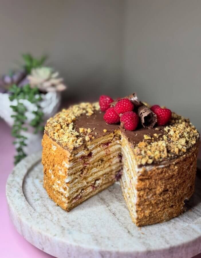 4 New Louisville Restaurants (+2 New Menus!) to Try This Month - 9 A layered cake with chopped nuts on top, garnished with chocolate curls and fresh raspberries, sits on a round marble platter. A slice has been cut to show the cake’s layers.