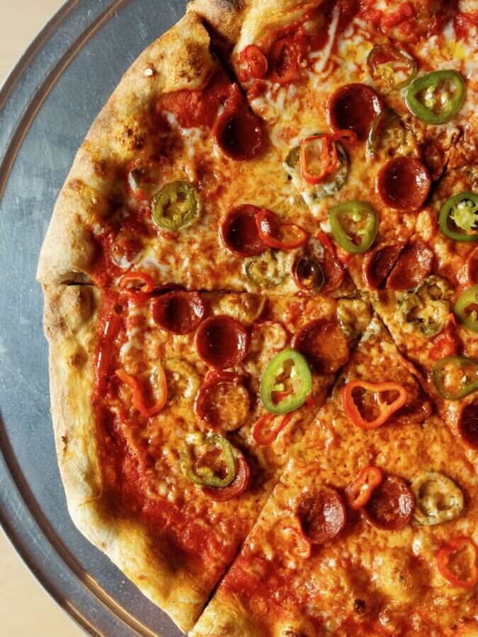 4 New Louisville Restaurants (+2 New Menus!) to Try This Month - 10 A close-up of a pepperoni pizza topped with sliced green and red jalapeños, displayed on a metal tray.