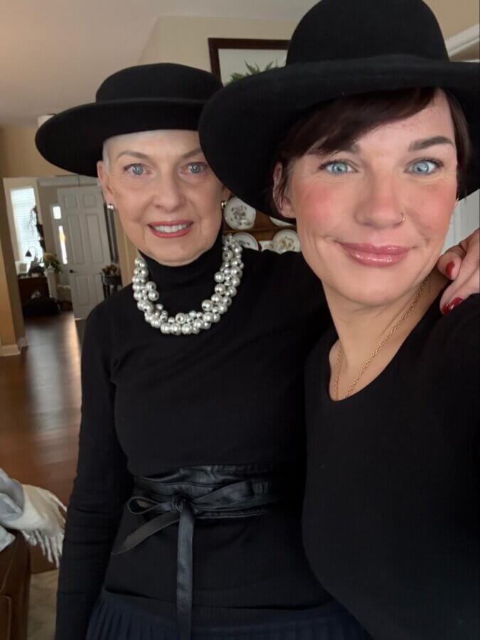 This Master Memphis Tattoo Artist Helps Women Feel Whole Again - 4 Two women wearing black hats and black tops pose for a selfie indoors; one wears a large pearl necklace and the other has a nose ring, both capturing their unique FACES in true Nicolette Tomblyn style.
