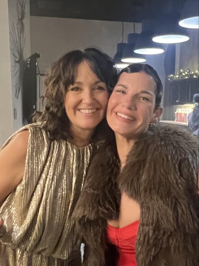 This Master Memphis Tattoo Artist Helps Women Feel Whole Again - 7 Nicolette Tomblyn and a friend smile and pose together indoors, one wearing a shiny silver dress and the other in a fur coat over a red top, capturing the spirit of FACES.