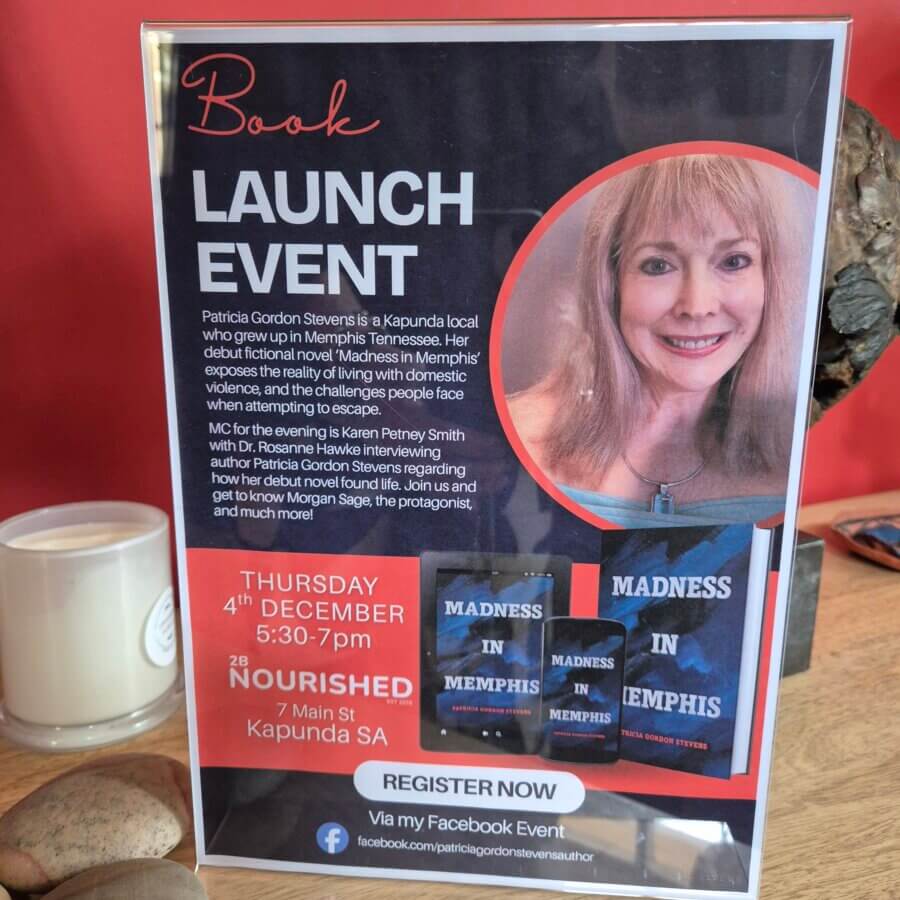 Promotional sign for a book launch event, featuring a photo of an author, event details, and the cover of the book "Madness in Memphis" displayed on a clear stand.