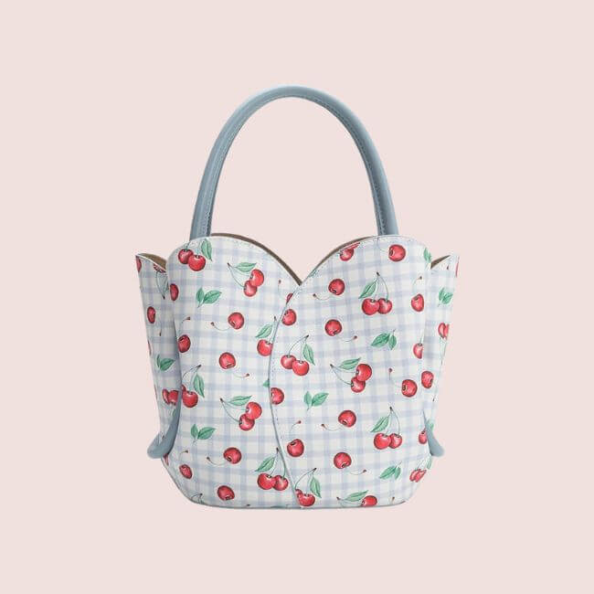 15 Memphis FINDS to Welcome Spring - 9 Blue-handled handbag with a scalloped top, featuring a blue and white checkered pattern and a red cherry print on a light pink background—one of the standout Memphis finds for February.