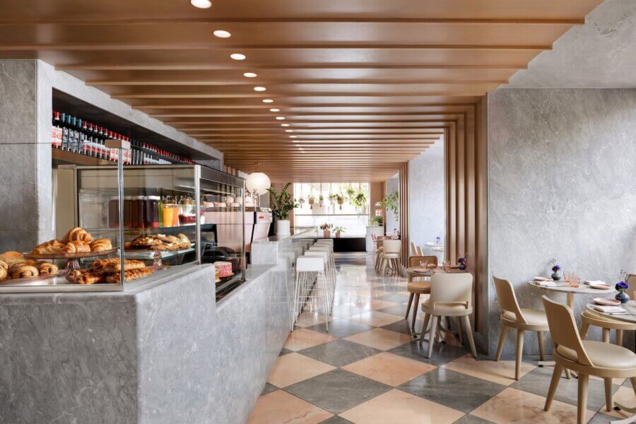 Nashville Steals, Deals & Announcements: March 2026 - 3 Modern cafe interior with marble surfaces, wooden ceiling panels, pastry display, checkered floor, and neatly arranged tables and chairs.