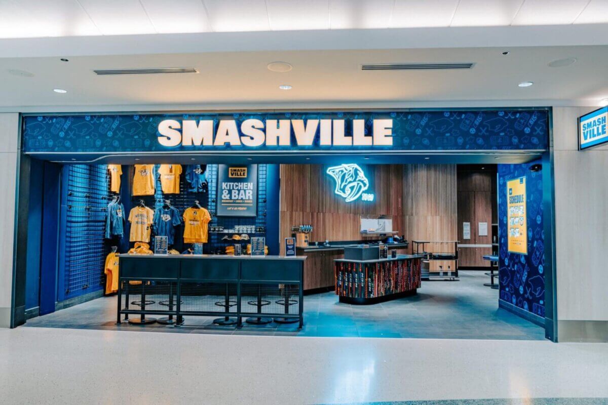 A Smashville store with blue walls, Nashville Predators merchandise, and a bar area inside, located in what appears to be an airport concourse and featured in the BNA Dining Guide.