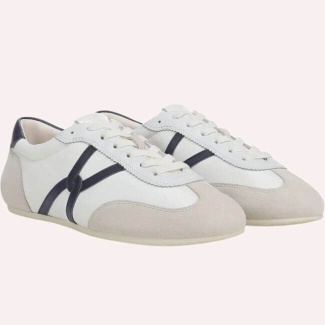 6 Spring 2026 Fashion Trends + How to Wear Them - 20 A pair of white lace-up sneakers with beige suede toe caps and dark navy side stripe accents, displayed on a neutral background.