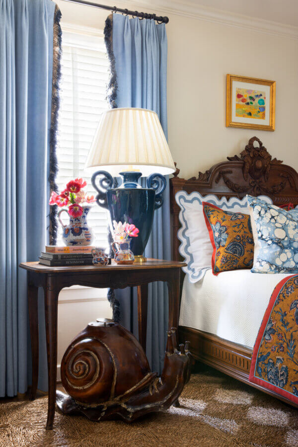 Something Old, Something New: How Ellie Christopher Makes Antiques Feel Fresh - 9 A bedroom with blue curtains and a snail under a table with a lamp