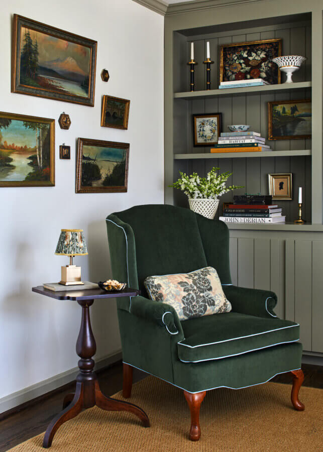 Something Old, Something New: How Ellie Christopher Makes Antiques Feel Fresh - 5 A green chair in front of a decorated shelves with framed pictures on the wall and a side table with a lamp