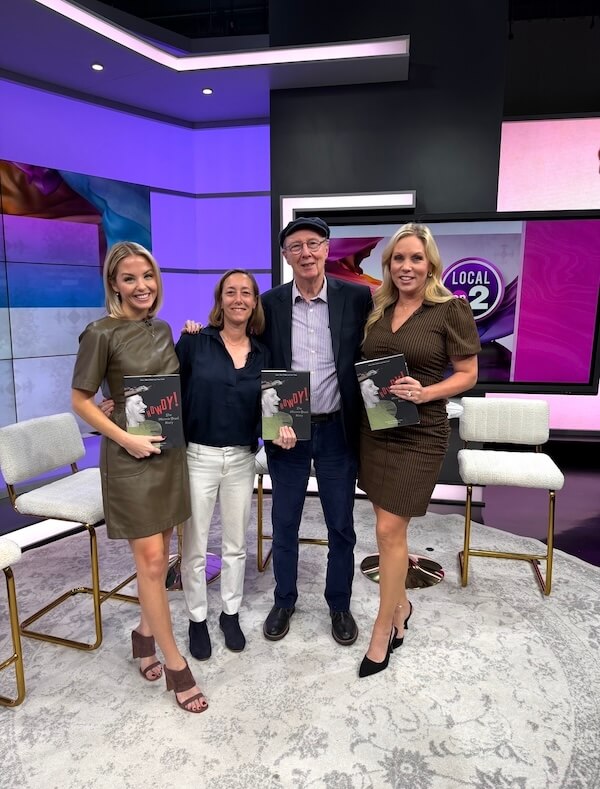 She’s Putting Nashville’s Hidden History on the Map - 2 Four people stand indoors on a TV studio set, smiling at the camera, with two women—one being Dr. Mary Ellen Pethel—holding books. There are empty chairs, colorful backgrounds, and a screen displaying "LOCAL 2.