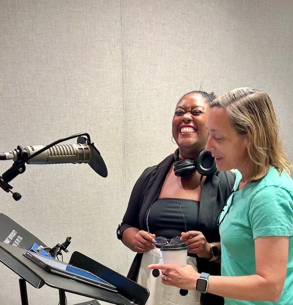 She’s Putting Nashville’s Hidden History on the Map - 5 Dr. Mary Ellen Pethel stands next to another woman by a microphone and music stand in a recording studio; one smiles broadly while the other points at a script.