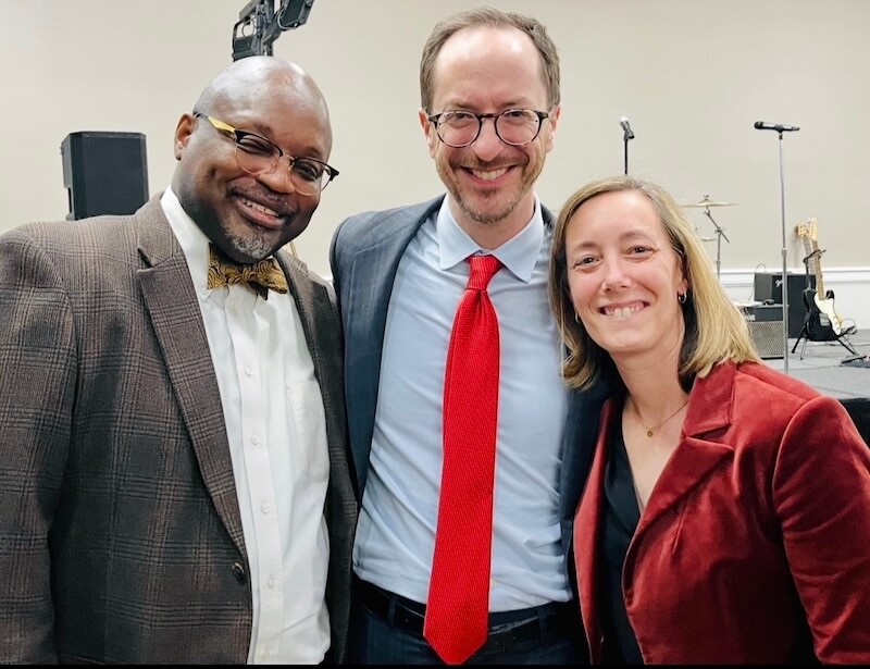 She’s Putting Nashville’s Hidden History on the Map - 6 Three adults in business attire, including Dr. Mary Ellen Pethel, stand together indoors, smiling at the camera. Musical instruments and microphones are visible in the background.