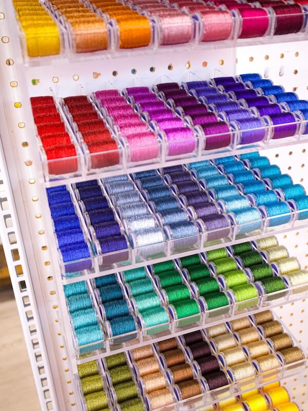9 New Nashville Retail Spots to Explore - 6 Rows of colorful embroidery threads organized by shade on clear shelves attached to a white pegboard invite you to explore.