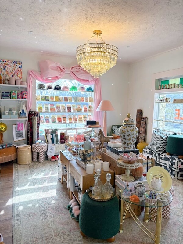 9 New Nashville Retail Spots to Explore - 7 A well-lit boutique room in Nashville retail with a chandelier, various gift items on tables, decorative objects, and a display of greeting cards by a large window—perfect for those looking to explore new retail spots.