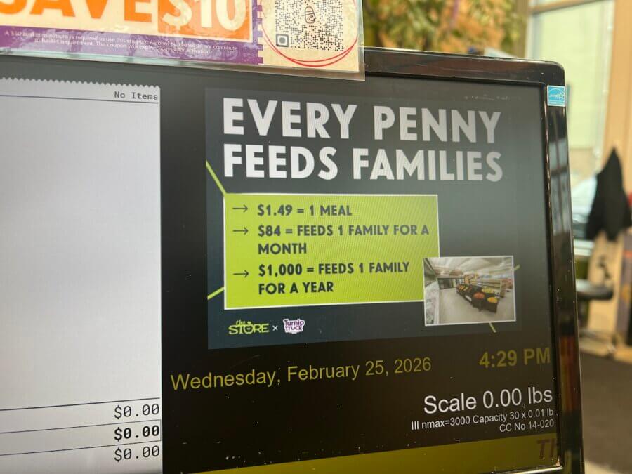 Turnip Truck & 'The Store' Are Rounding Up for Neighbors in Need - 5 A sign at the store displays donation amounts: $1.49 equals one meal, $84 feeds a family for a month, and $1,000 feeds a family for a year. A shopping cart image—like those at Turnip Truck—appears. Timestamp reads 4:29 PM.