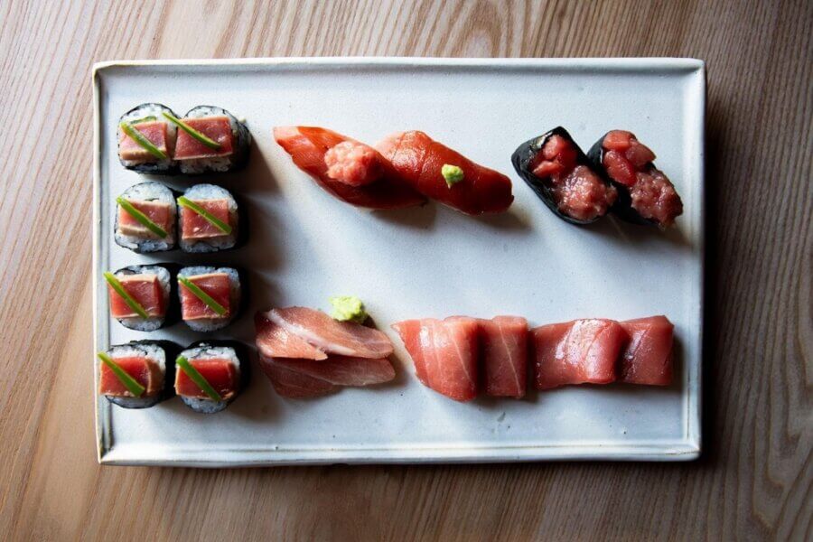 Sushi in Nashville is a THING. Here's Your Guide. - 4 A rectangular plate with assorted sushi pieces, including maki rolls, nigiri, and gunkan-maki with various fish toppings, served on a wooden table in a cozy Nashville setting.