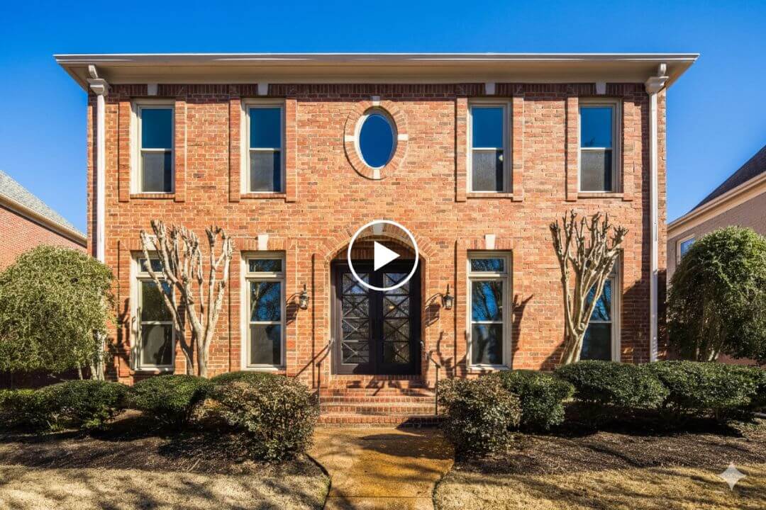 Two-story red brick house at 186 N White Station Rd, Memphis, with six tall windows, double front doors, an oval window above the entrance, trimmed bushes, and bare trees in the front yard.