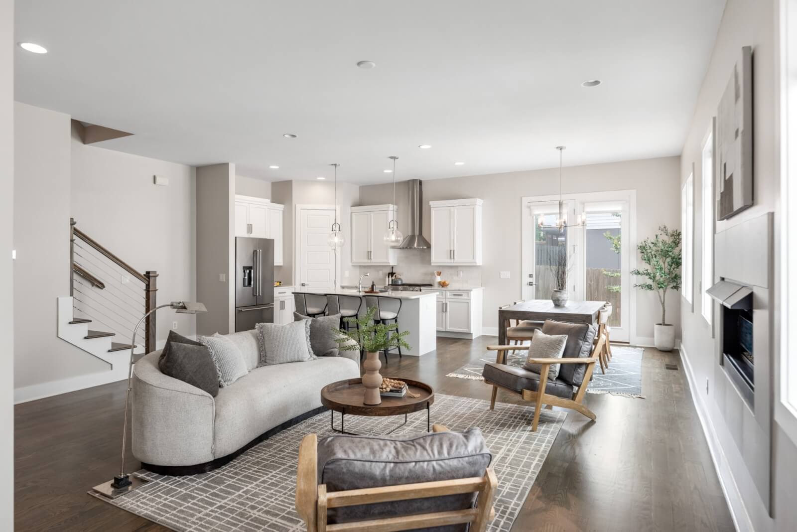 Open-concept living room and kitchen on Southside Ave, Nashville TN, featuring modern furnishings, neutral colors, hardwood floors, and large windows bringing in natural light.