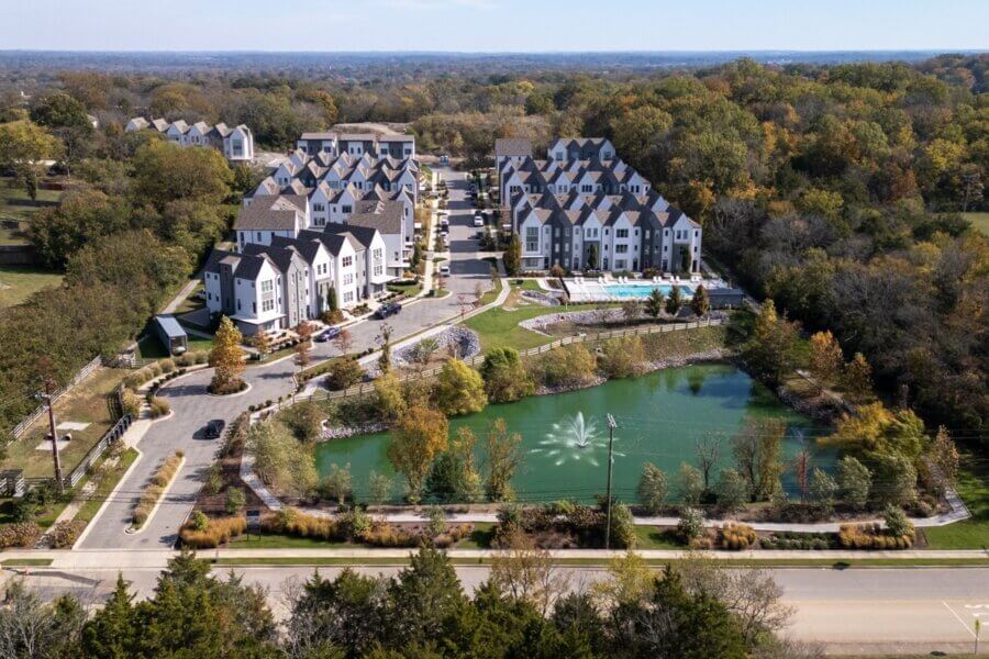 Aerial view of a residential apartment complex on 257 Arrowhead Dr, Nashville, surrounded by trees, featuring a pond with a fountain, outdoor pool, and parking areas.
