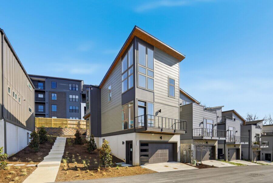 Modern three-story townhouse with large windows, a balcony, and attached garage, located along Edwin Circle in Nashville, with neighboring homes and an apartment building in the background.