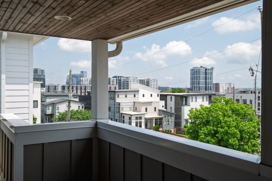 View from a covered balcony on Southside Ave overlooking modern residential buildings and distant high-rises under a partly cloudy Nashville sky.