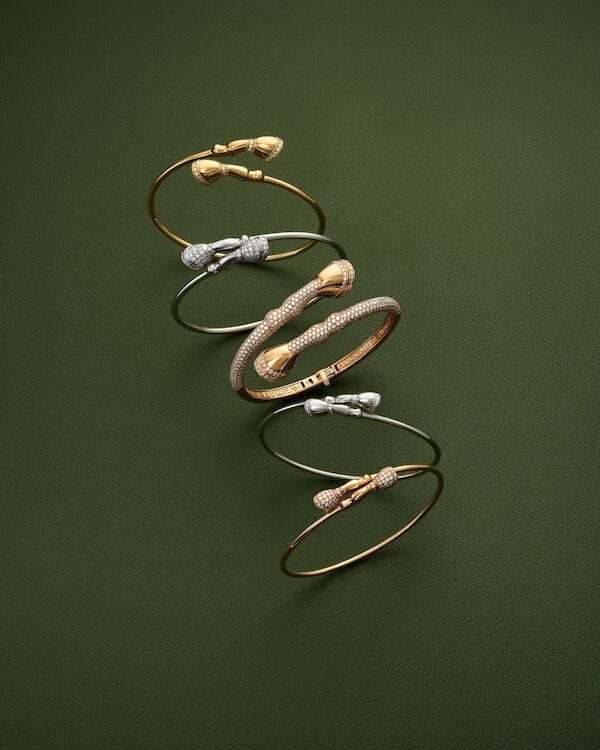 Karina Brez Jewelry: From Florida Horse Country to the Equestrian World Cup Spotlight - 5 Five elegant gold and silver bracelets from Karina Brez Jewelry, each with decorative ends, are arranged vertically on a textured dark green background.