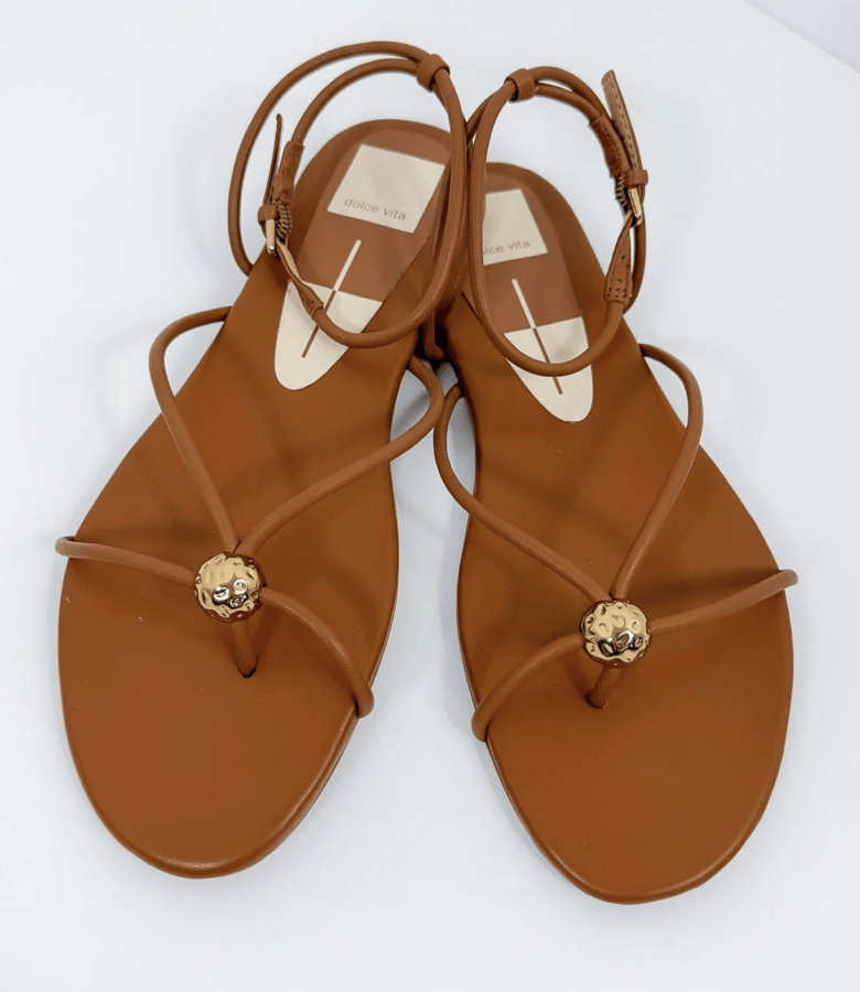 19 Fresh FINDS Around BHAM: Closet Refreshers, Entertaining Picks & More - 8 A pair of brown strappy flat sandals with gold decorative accents on the toe straps, displayed on a white background.